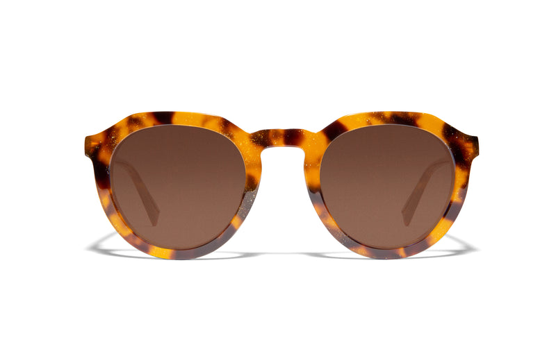 Image of Cheeterz Club eyewear. Photo of round sunglasses with brown tinted lenses. The frames are medium width with glitter infused golden brown and black color and spotted print, suitable for square, oval, and oblong face shapes. 